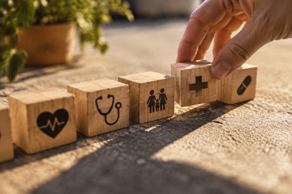 Une main aligne des cubes en bois portant des symboles médicaux pour illustrer la comparaison de mutuelle santé.
